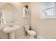 Bright half bathroom with pedestal sink, cabinet, and window at 7833 Bandit Dr, Castle Rock, CO 80108