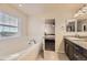 Bright bathroom featuring a soaking tub, granite countertops, and a doorway to the adjacent bedroom at 7833 Bandit Dr, Castle Rock, CO 80108