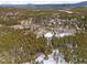Aerial view showcasing a wooded neighborhood with snow-covered land and the house on acreage at 9239 Black Mountain Dr, Conifer, CO 80433