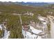 Aerial view showcases the wooded area and snow-covered acreage featuring a winding driveway leading to the house at 9239 Black Mountain Dr, Conifer, CO 80433