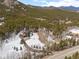 An aerial view of the property shows trees and a winding driveway leading to the house on the snow-covered lot at 9239 Black Mountain Dr, Conifer, CO 80433