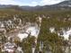 An aerial view of a wooded area showing the snow-covered lot featuring a winding driveway to the house at 9239 Black Mountain Dr, Conifer, CO 80433