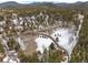Aerial view showing the wooded acreage and the winding driveway on a snow-covered lot with mountain views at 9239 Black Mountain Dr, Conifer, CO 80433