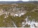 Aerial view showcases a wooded area with snow-covered acreage, trees, and a house on the lot at 9239 Black Mountain Dr, Conifer, CO 80433
