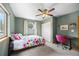 Bright bedroom with floral comforter, ceiling fan, desk and octagon window at 9239 Black Mountain Dr, Conifer, CO 80433