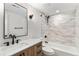 Modern bathroom features a wood vanity with marble countertop, and a shower-tub combo with stylish tile at 380 S Xanadu St, Aurora, CO 80012