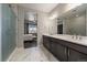 Bright bathroom featuring dual sinks, sleek vanity, marble floors, and a glass enclosed shower at 5611 Saddle Skirt St, Parker, CO 80134