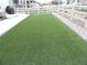Spacious backyard featuring a green artificial lawn, a white fence, and a concrete patio at 5223 Gray Wolf Ln, Castle Rock, CO 80104