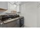 Modern laundry room featuring gray front-load washer and dryer, with decorative chandelier and convenient upper cabinet at 11188 Latigo Ln, Parker, CO 80138