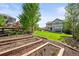 Well-manicured backyard showcases raised garden beds, lush lawn, mature trees, and an outdoor dining set at 2090 Bellavista St, Castle Rock, CO 80109