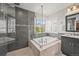 Luxurious bathroom features a glass-enclosed shower and a soaking tub with natural light streaming through plantation shutters at 2090 Bellavista St, Castle Rock, CO 80109