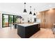 Open kitchen and dining area featuring a black island, pendant lights, wood cabinets, and exterior view at 516 Grant Ave, Louisville, CO 80027