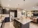 Open kitchen with island seating, stainless appliances, dark cabinetry, and a view into the living area at 10968 Pastel Pt, Parker, CO 80134