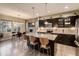 Modern kitchen with dark cabinets, a large center island, stainless steel appliances, and an open dining area at 10968 Pastel Pt, Parker, CO 80134