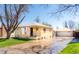 Charming yellow brick home with a well-manicured lawn, an American flag, and a detached two-car garage at 2548 S Zurich Ct, Denver, CO 80219