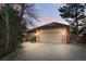 Exterior view of a home featuring a two-car garage, brick facade, and a driveway, set among mature trees at 4212 E Orchard Pl, Centennial, CO 80121