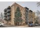Brick apartment building with modern balconies and mature trees, offering a contemporary urban living experience at 65 N Clarkson St # 604, Denver, CO 80218