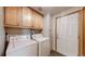 Functional laundry room with washer, dryer, storage cabinets, and access to the exterior at 13673 Cook St, Thornton, CO 80602