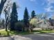 Home exterior showing mature trees, a white picket fence and a glimpse of the garage at 6375 E 6Th Avenue Pkwy, Denver, CO 80220