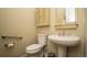 Bathroom with toilet and pedestal sink with overhead lighting and wooden cabinet at 11259 Kalispell St, Commerce City, CO 80022
