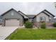 Charming home featuring a two-car garage, stone accents, a well-manicured lawn, and tasteful landscaping at 11259 Kalispell St, Commerce City, CO 80022