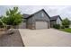 Three-car garage with stone accents, with a large driveway and landscaping at 11259 Kalispell St, Commerce City, CO 80022