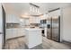 Bright kitchen with gray floors, white cabinets, stainless steel refrigerator, and stone countertops at 1832 Simms St, Lakewood, CO 80215