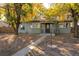 Charming single-story home with green siding, mature trees and a walkway to the entrance at 801 S Shoshone St, Denver, CO 80223