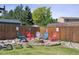 Backyard fire pit area with wooden fence and colorful Adirondack chairs at 8445 Lamar Dr, Arvada, CO 80003