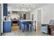 Open-concept kitchen with blue cabinets, island seating, and stainless steel appliances, seamlessly flowing into the living area at 8445 Lamar Dr, Arvada, CO 80003