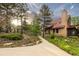 Inviting home with a stone chimney, copper roof, and a welcoming walkway amidst lush greenery and sunlit trees at 116 Ramona Rd, Golden, CO 80403