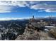 A scenic vista of a hiker atop a rocky mountain, overlooking snow-dusted forests and distant clouds at 116 Ramona Rd, Golden, CO 80403