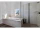 Bright bathroom features a soaking tub beneath a window and a frameless glass shower with tiled walls at 2224 W 37Th Ave, Denver, CO 80211