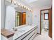 Well-lit bathroom with a large mirror, double sinks, and doorway to the toilet and shower at 11686 W 74Th Way, Arvada, CO 80005