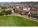An aerial view reveals a residential neighborhood bordering a lush green golf course under a clear, sunny sky at 1344 Royal Troon Dr, Castle Rock, CO 80104