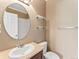 Bathroom with light pink walls, sink with dark wood cabinet, round mirror and glass shelves at 1344 Royal Troon Dr, Castle Rock, CO 80104