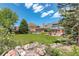 Manicured backyard with stone creek, mature trees, and lush lawn offer a tranquil and picturesque view at 9141 Roundtree Dr, Highlands Ranch, CO 80126