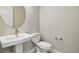 A modern powder room with a pedestal sink, round mirror, and white toilet at 9329 Russell Cir, Arvada, CO 80007
