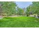 Large backyard with lush green lawn, mature trees, and a wood fence at 6598 S Telluride St, Aurora, CO 80016
