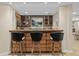 Basement wet bar with wine refrigerator, wooden cabinetry and seating for three at 5320 S Race Ct, Greenwood Village, CO 80121