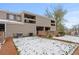 An exterior view of a tan townhouse featuring a brick facade, balcony, porch, and snowy outdoor area at 5512 S Greenwood St, Littleton, CO 80120