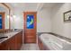 Elegant bathroom featuring a soaking tub, granite countertop, and artistic door at 9107 S Deer Creek Canyon Rd, Littleton, CO 80127