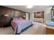 Spacious bedroom featuring wood paneling, neutral carpet, and comfortable furnishings at 9107 S Deer Creek Canyon Rd, Littleton, CO 80127