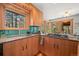 Modern kitchen with wood cabinetry, stainless steel appliances, and blue tile backsplash at 9107 S Deer Creek Canyon Rd, Littleton, CO 80127