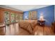 Cozy main bedroom featuring hardwood floors, blue walls, and sliding doors to the backyard at 9107 S Deer Creek Canyon Rd, Littleton, CO 80127