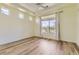 Bright bedroom featuring wood-look floors, tray ceiling, and large windows with neighborhood views at 5495 Espana Ct, Denver, CO 80249