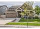 Charming two-story home featuring stone accents, neutral siding, a well-manicured lawn, and an attached two-car garage at 5495 Espana Ct, Denver, CO 80249