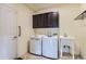 Functional laundry room with dark cabinets, modern washer and dryer, and utility sink for efficient cleaning at 5495 Espana Ct, Denver, CO 80249