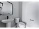 Modern half-bathroom with pedestal sink, black faucet, toilet, and sleek mirror at 1524 Ingalls St, Lakewood, CO 80214