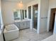 Luxurious primary bath with a soaking tub, glass shower, double vanity, and marble flooring at 9382 Quaker St, Arvada, CO 80007